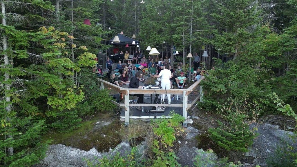 Spectacle en plein air sur une scène en bois, au milieu des arbres