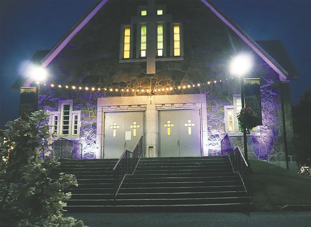 Façade de l'église illuminée en soirée, bannières du festival