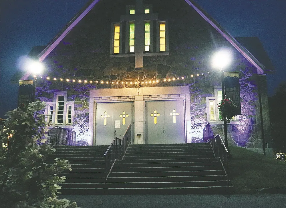 Façade de l'église illuminée en soirée, bannières du festival