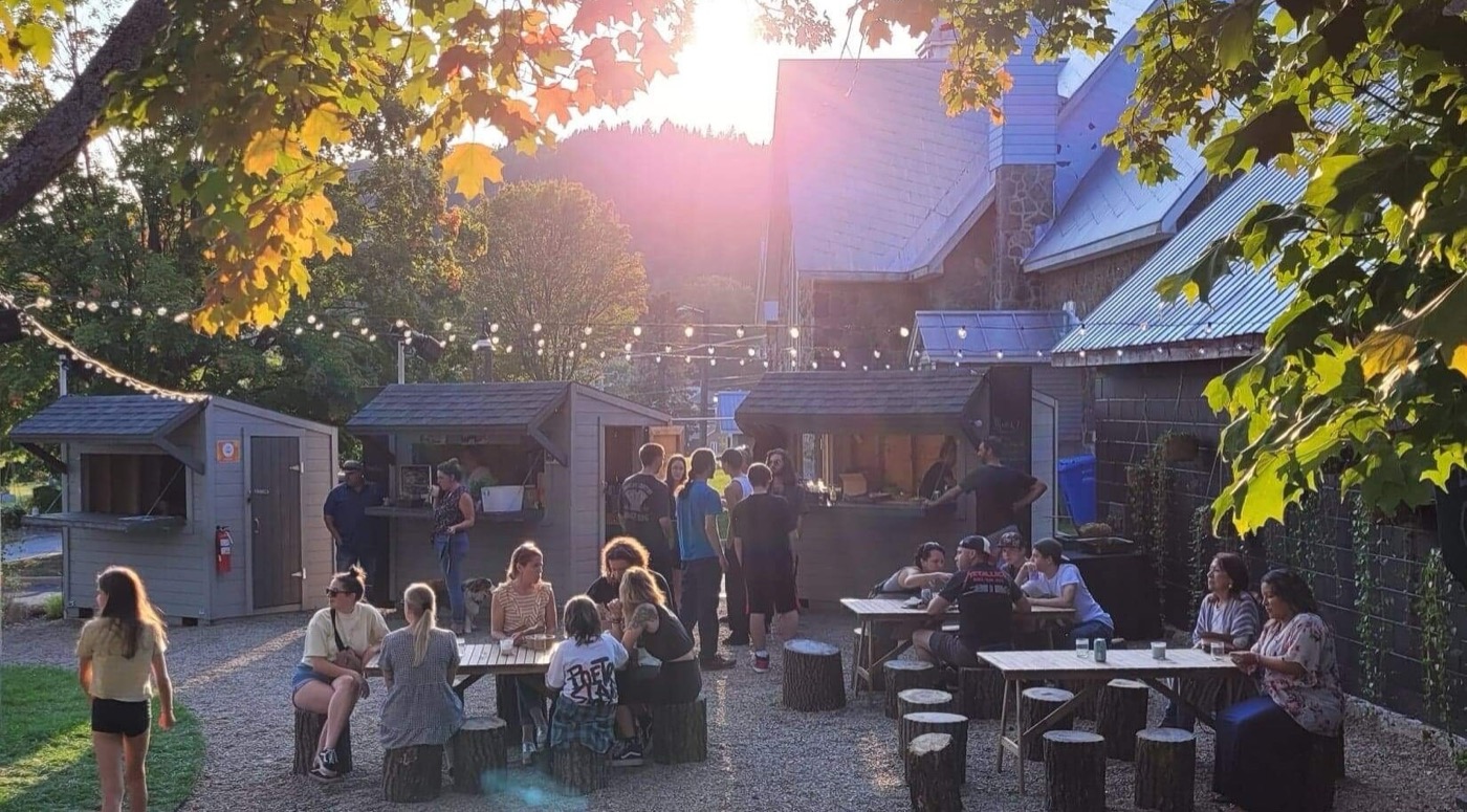Espace festif au soleil couchant — tables, guirlandes et kiosques