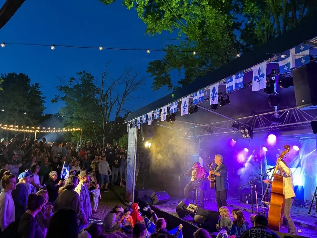 Groupe sur scène devant une foule, drapeaux et projecteurs