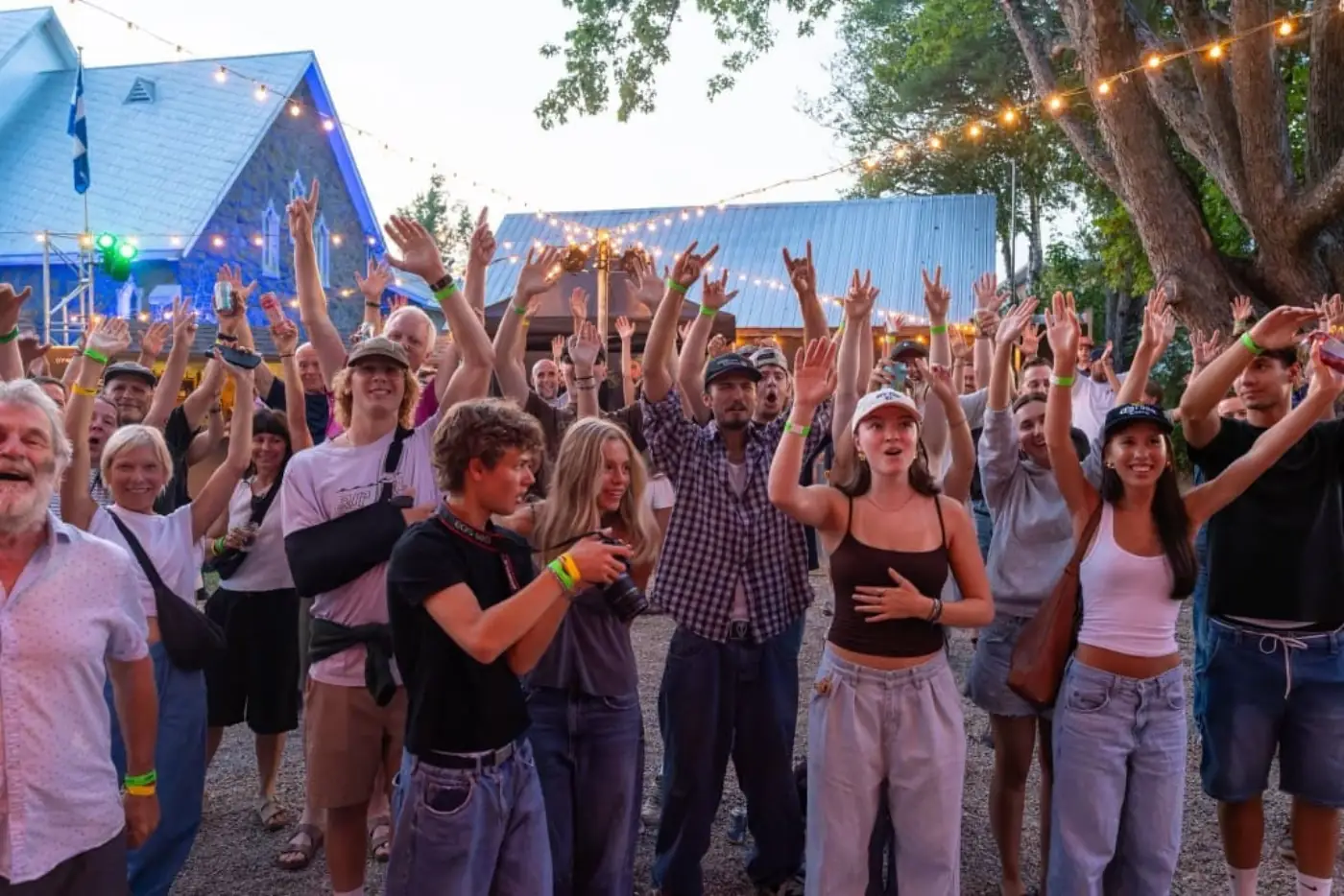 Foule en liesse en soirée, lumières suspendues au-dessus du village