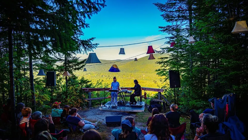 Concert au belvédère M2T : scène en bois, abat-jours suspendus et vue sur la vallée