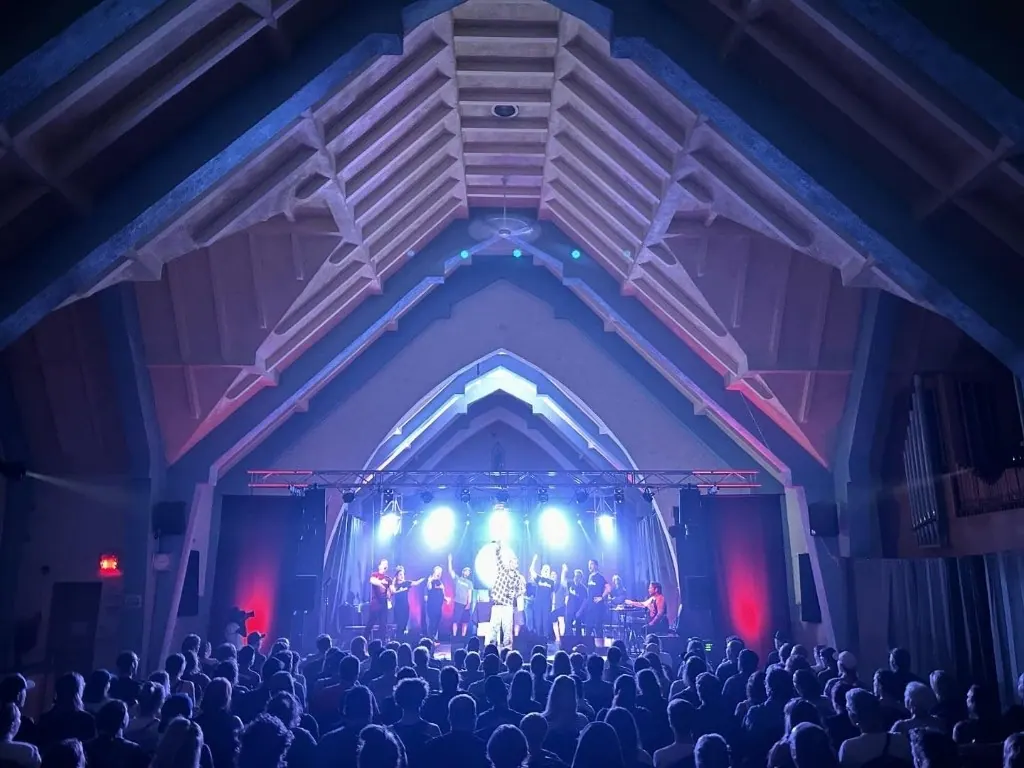 Concert dans l'église de Sainte-Brigitte-de-Laval : scène illuminée sous les voûtes et public en silhouette